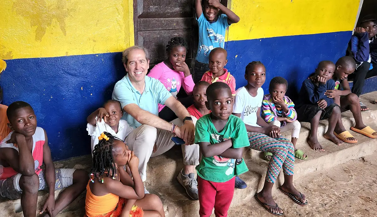 Un miembro de la fundación sentado con un grupo de niños del orfanato